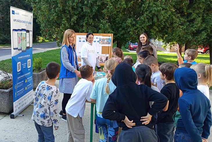 A group of children stands by the Populair stand